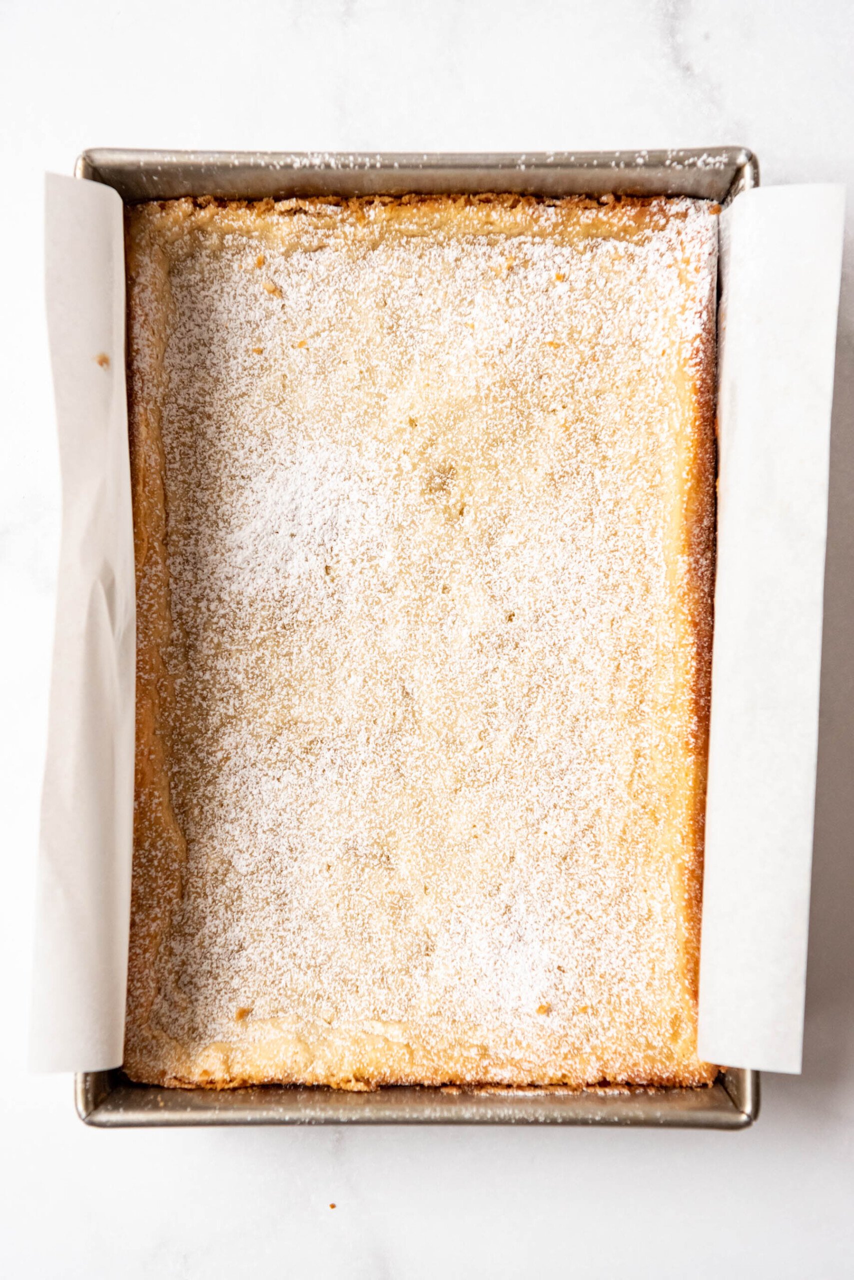 Top view of freshly baked gooey butter cake dusted with powdered sugar.