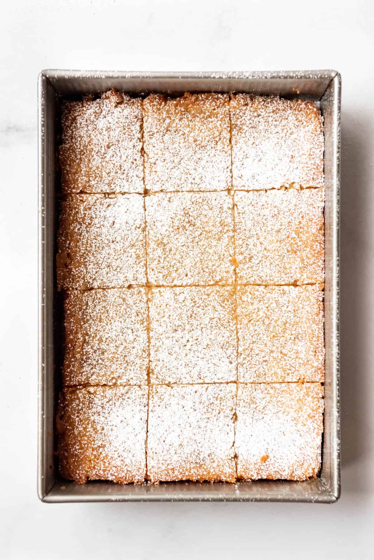 Top view of butter cake sliced into twelve servings in a baking pan.