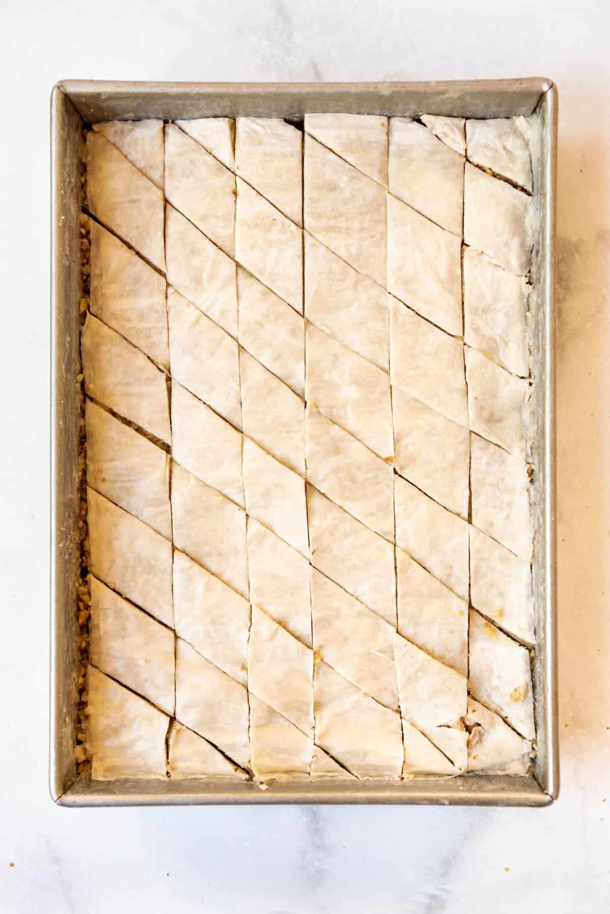 Diagonal lines cut into unbaked baklava to create diamond shapes.