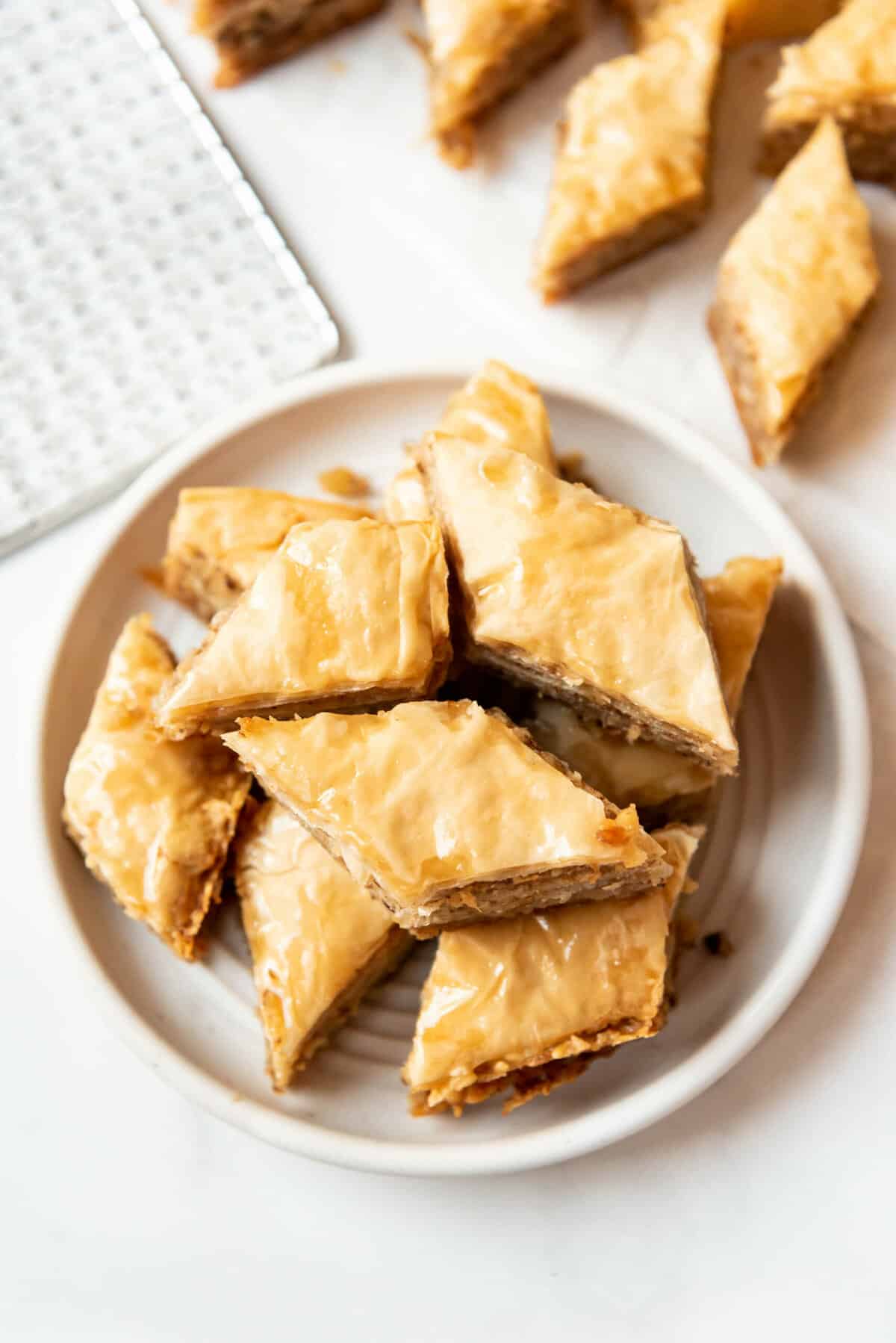 An overhead image of a white plate with diamond shaped pieces of honey baklava.