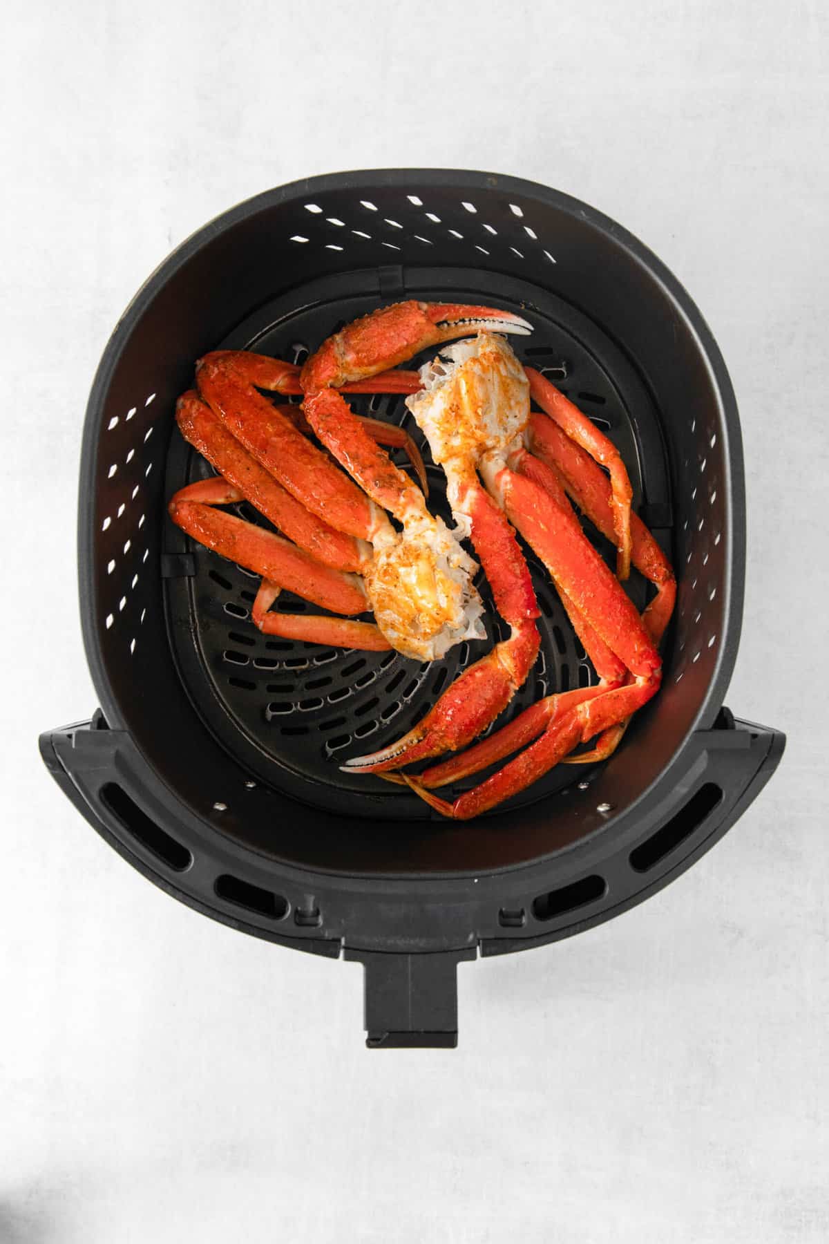Snow crab legs in the basket of an air fryer.