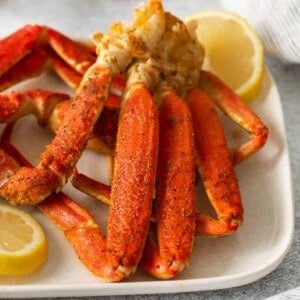 Cooked snow crab legs on a plate with lemon slices.