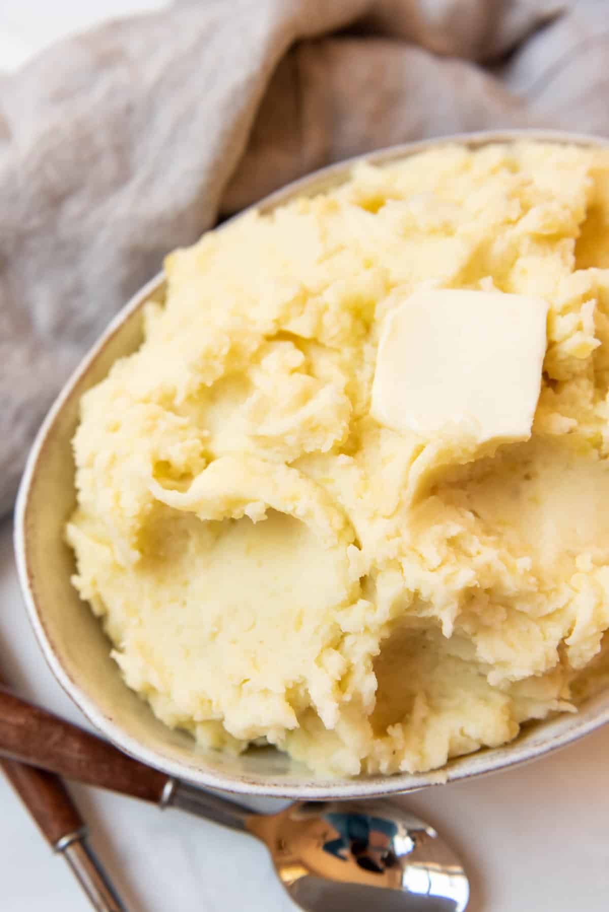 Top view of instant pot mashed potatoes in a serving dish with butter on top. 