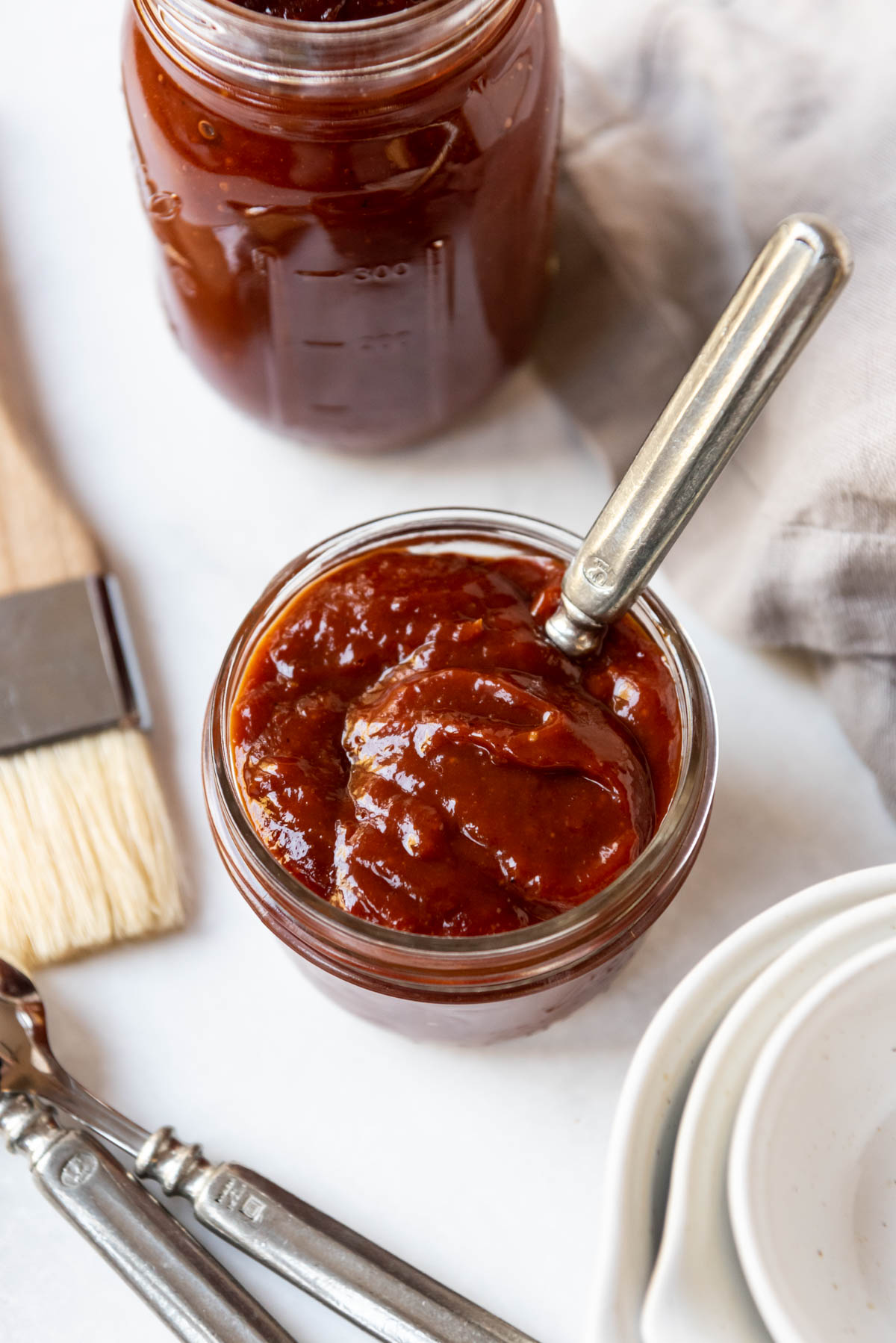 An overhead image of homemade Kansas City bbq sauce in a glass jar with a spoon in it.