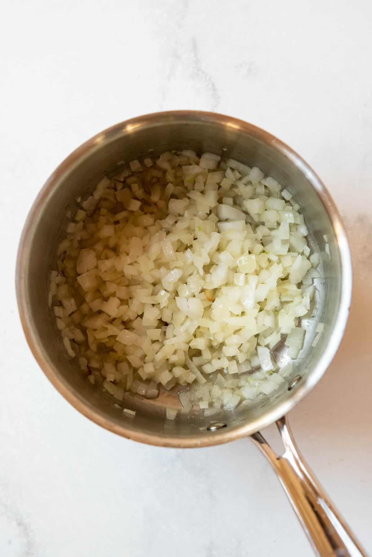 Sauteeing onions and garlic in a medium saucepan.