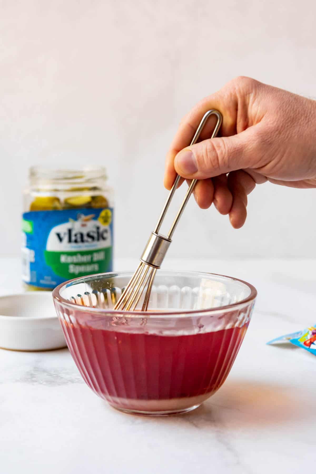 Whisking sugar and kool-aid into a bowl of pickle juice.