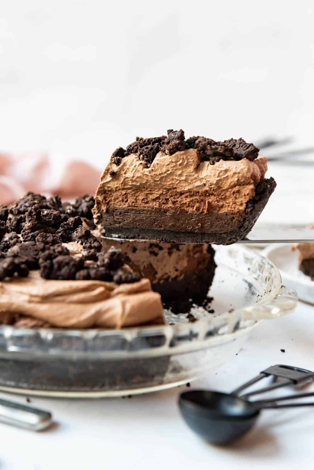 A slice of Mississippi mud pie being lifted out of a glass pie dish.