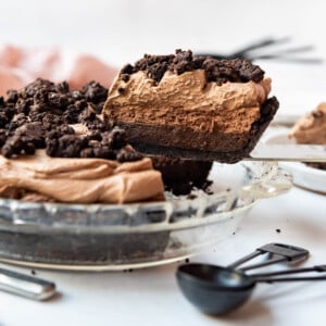 A slice of Mississippi mud pie being lifted out of a glass pie dish.