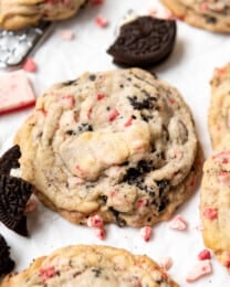 A peppermint Oreo cookie with scattered mint candies and broken Oreos around it.