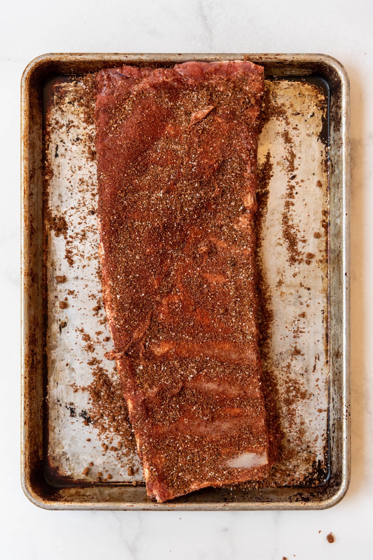 St. Louis ribs rubbed with dry rub on a baking sheet.