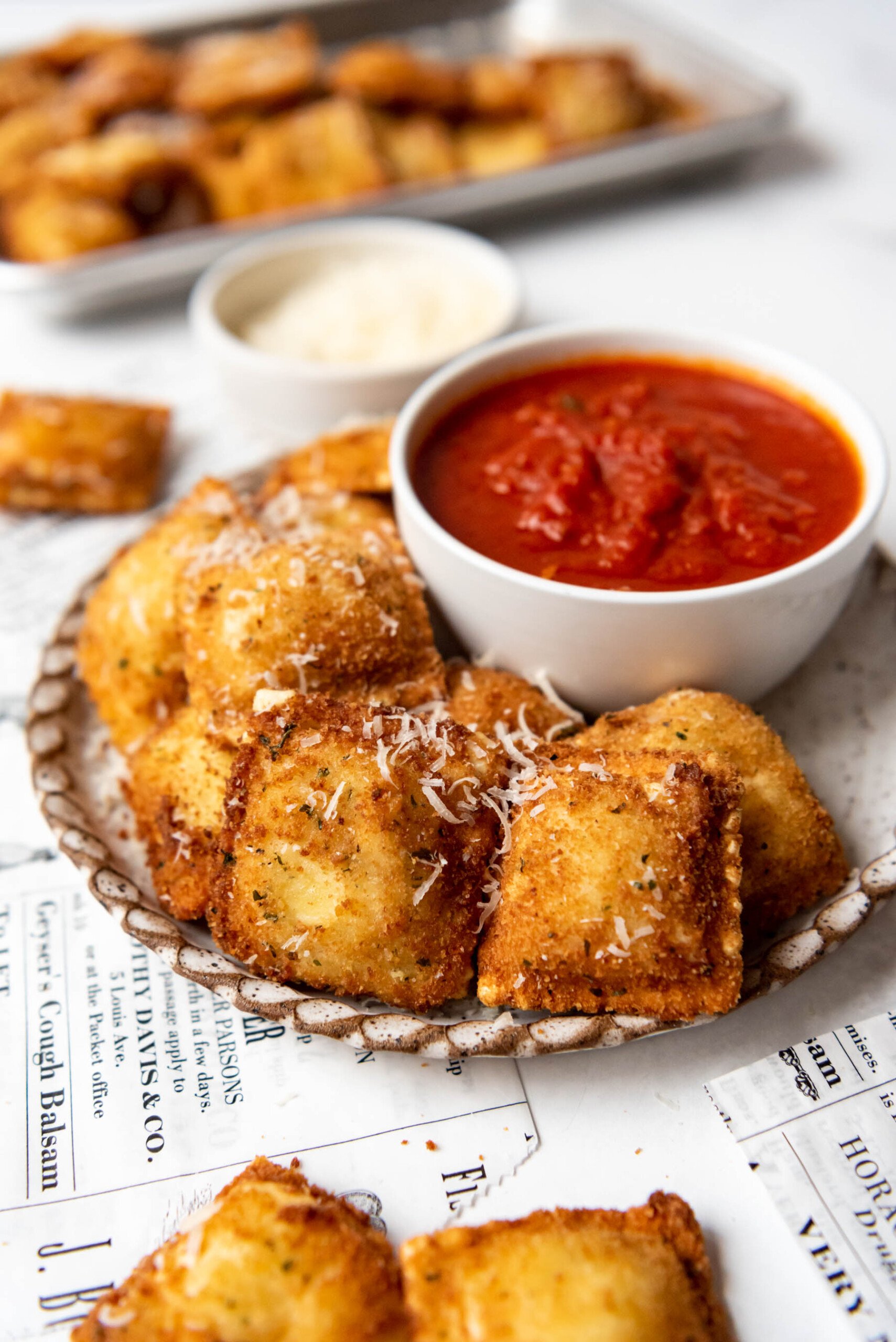 A plate of toasted ravioli with a bowl of marinara sauce for dipping.
