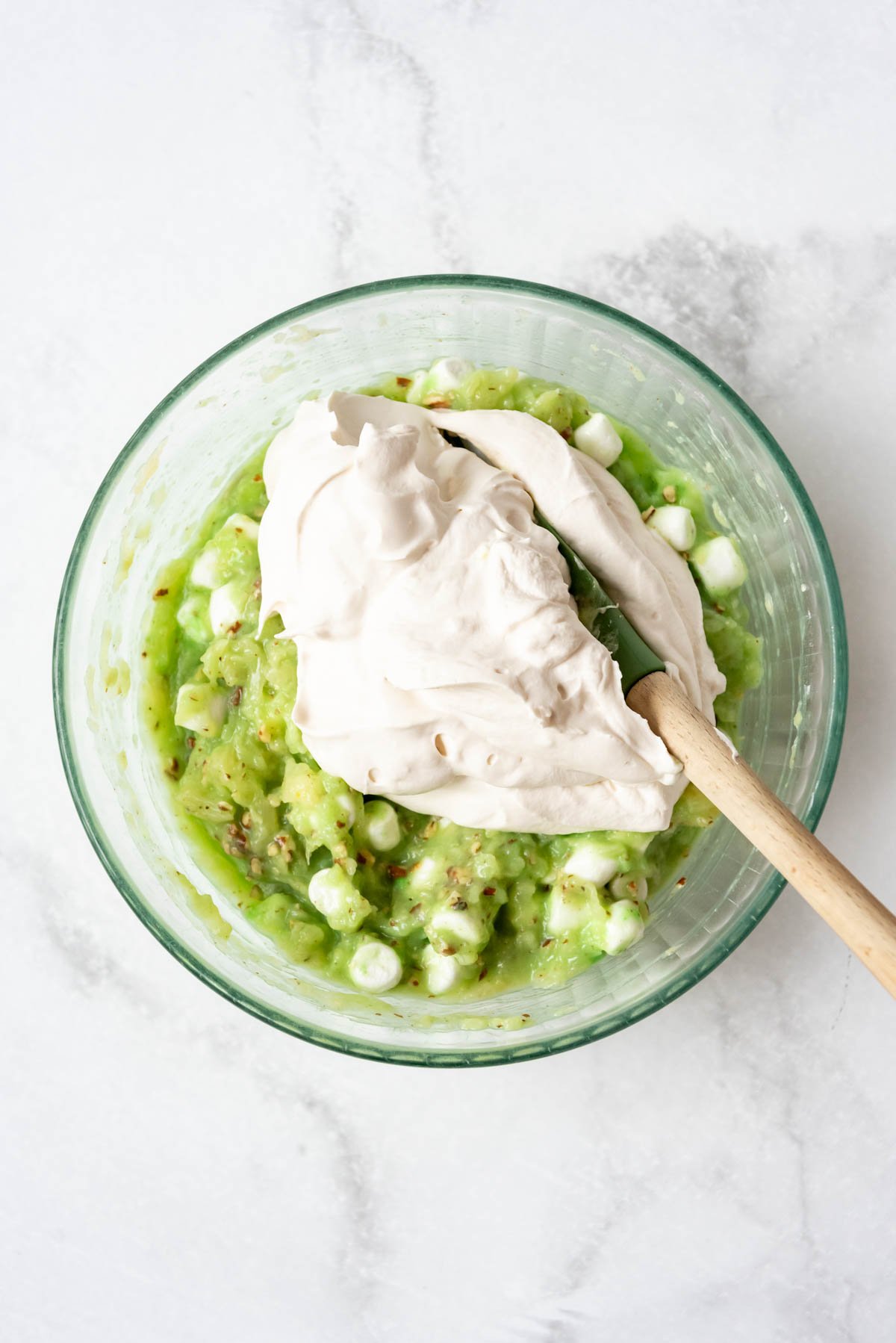 Folding whipped cream into watergate salad.