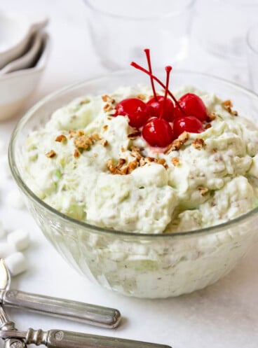 A large bowl of watergate salad with maraschino cherries on top.