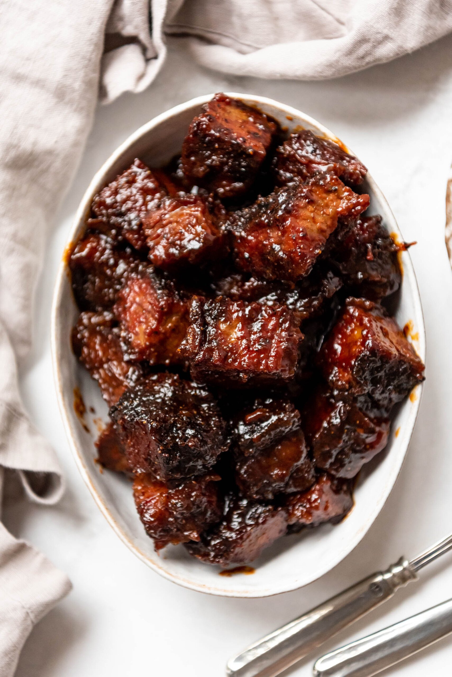 An overhead image of a bowl of smoked brisket burnt ends in an oval shaped bowl.
