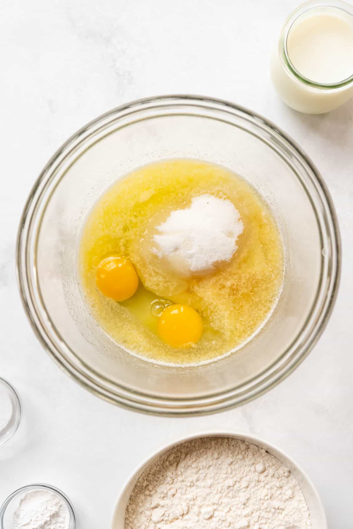 Eggs, melted butter, oil, sugar, and vanilla extract in a glass mixing bowl.