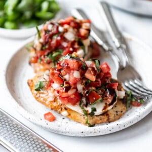 Bruschetta chicken on a plate with two forks.