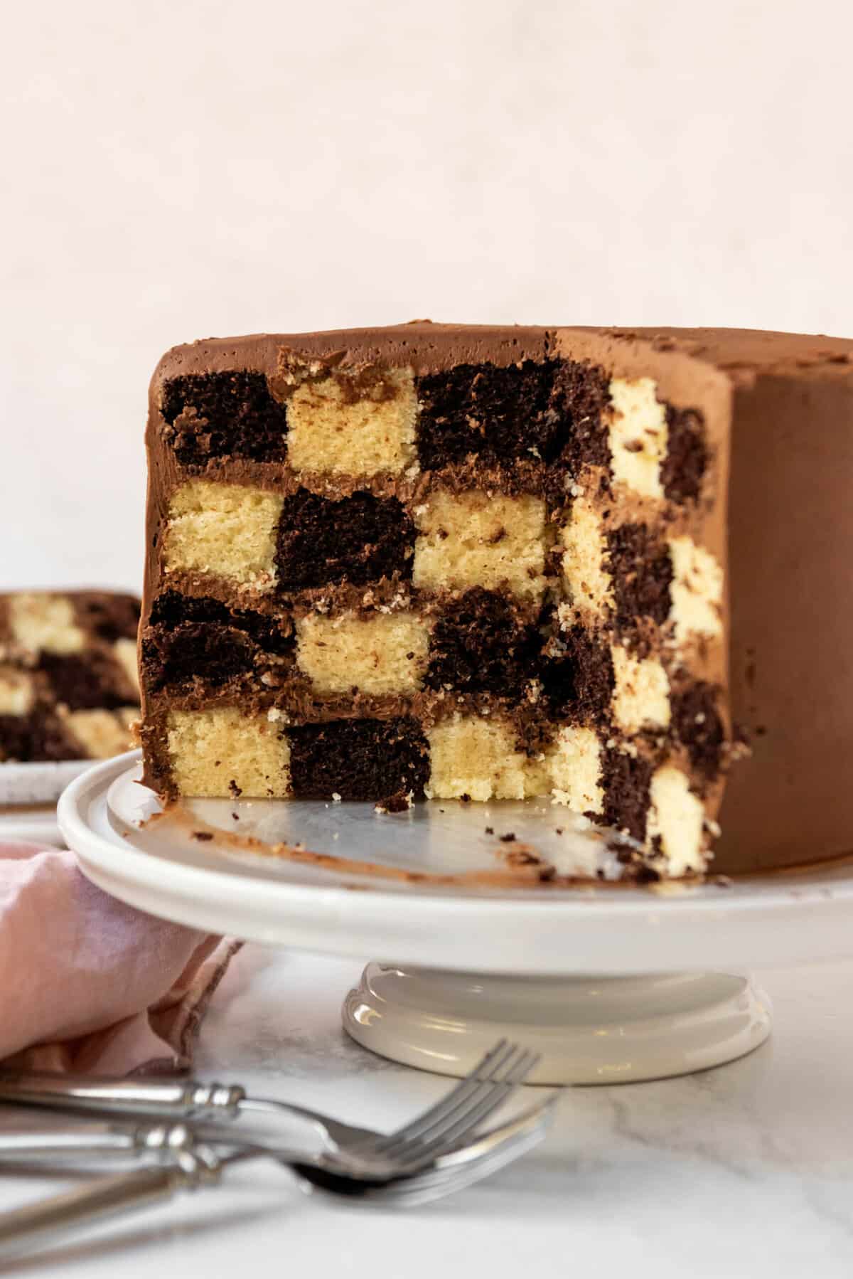 A cross section of a checkerboard cake on a white cake stand.