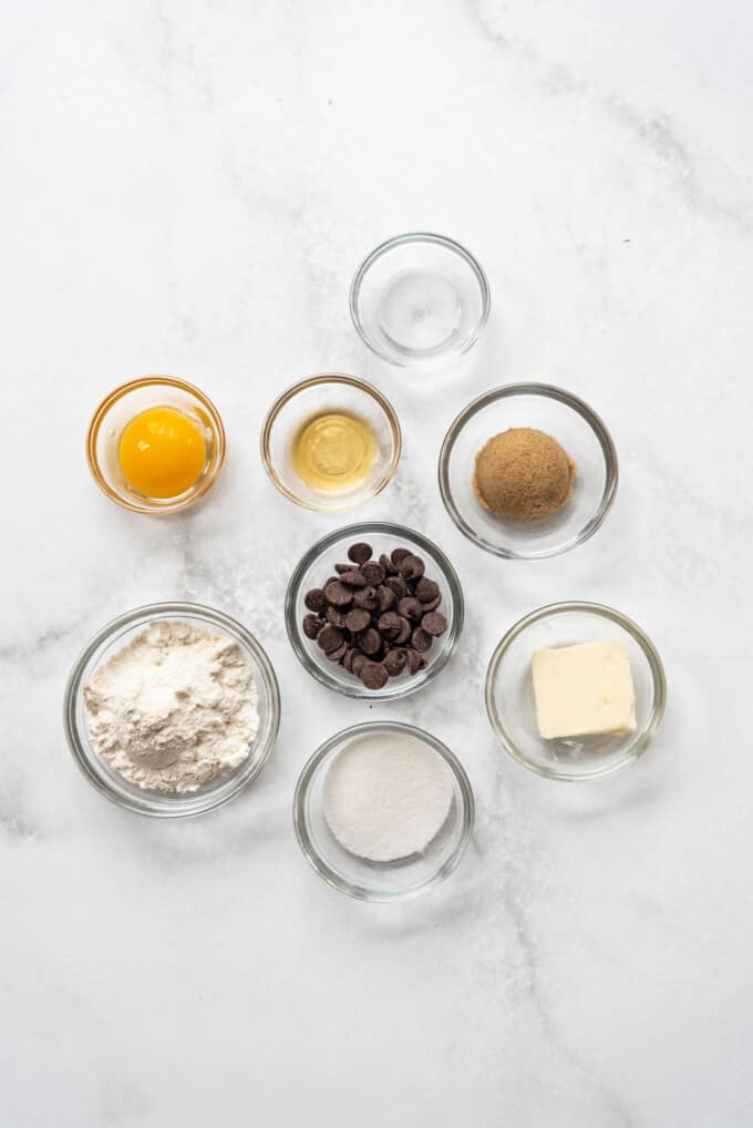 Ingredients for making a chocolate chip cookie in a mug in separate small bowls.
