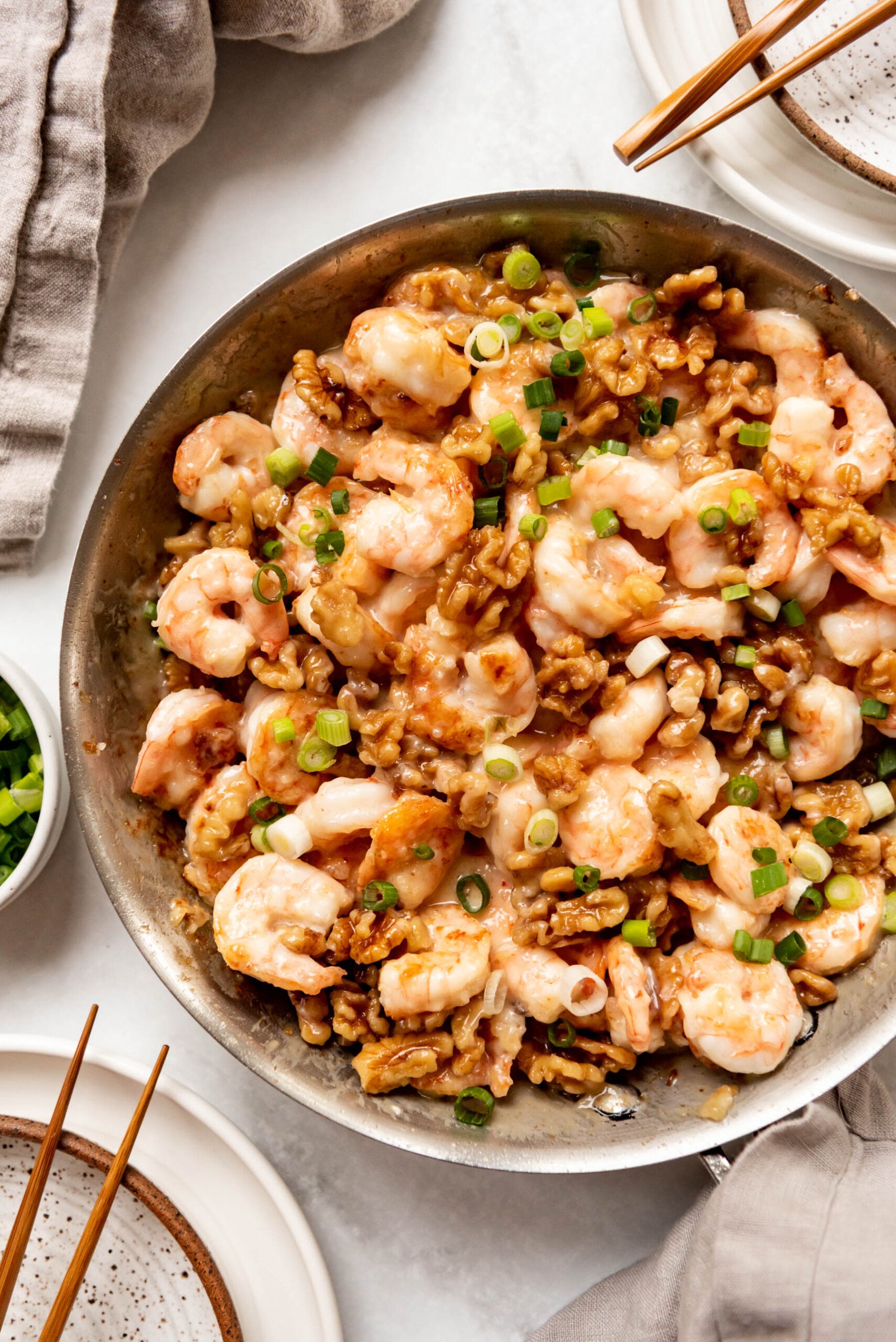 A pan full of honey walnut shrimp with green onions sprinkled on top.