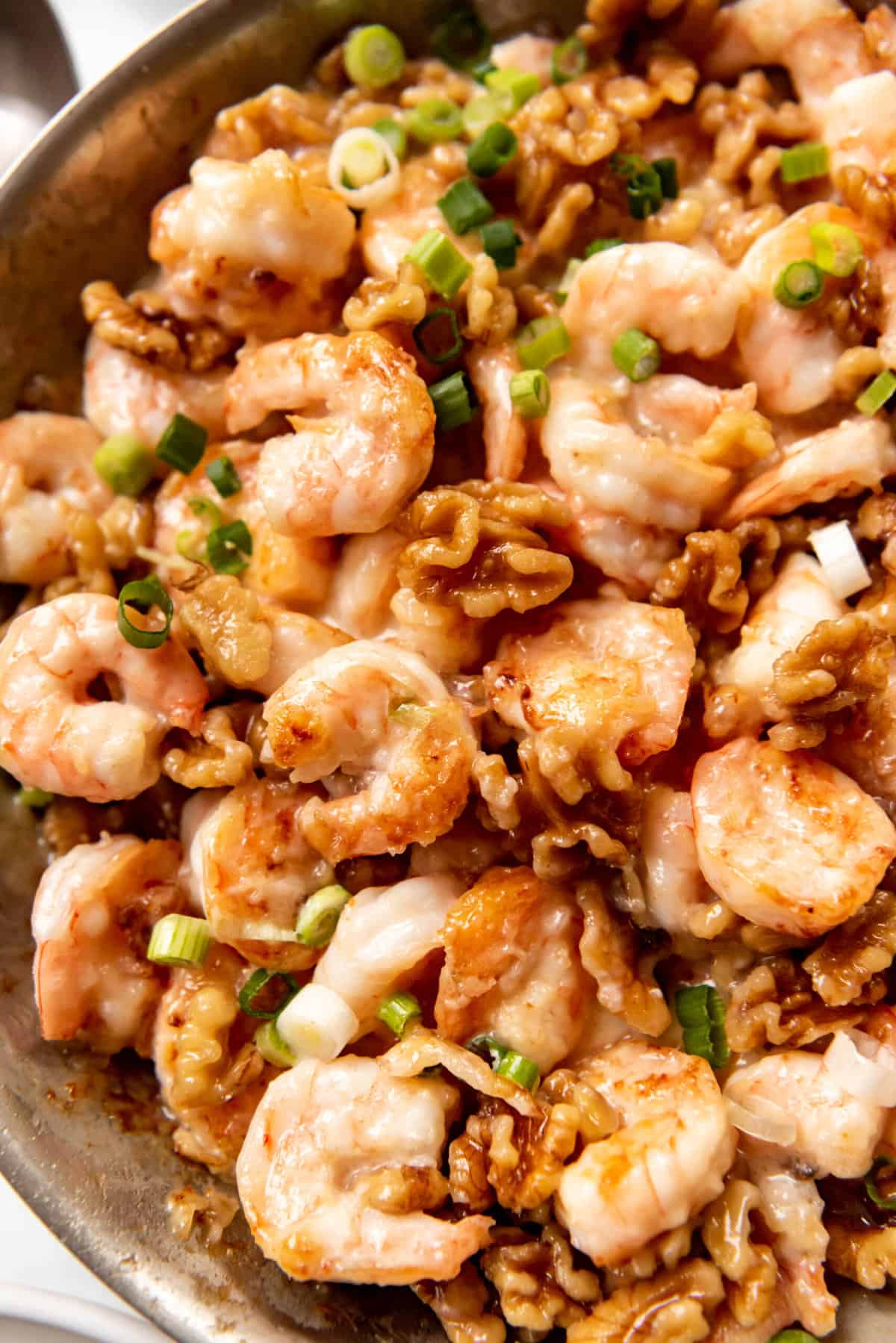 A close image of crispy cooked shrimp with walnuts in a creamy sweet honey sauce.