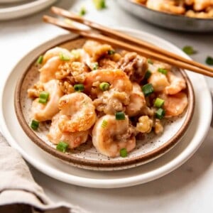 A plate of honey walnut shrimp with chopsticks on it.