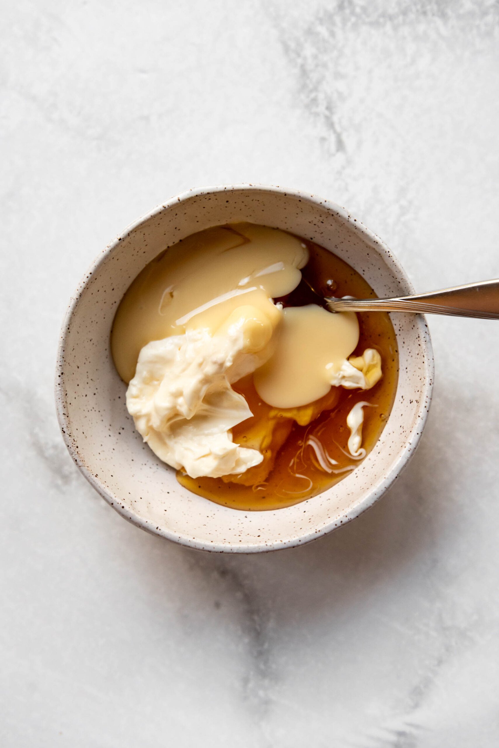Combining mayo, honey, and sweetened condensed milk in a bowl.