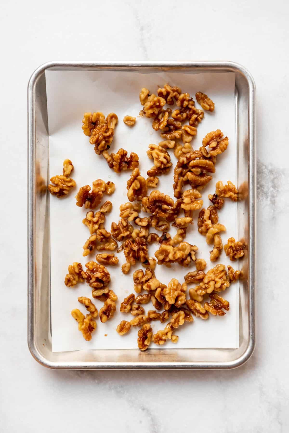 Walnuts spread on a baking sheet lined with parchment paper.