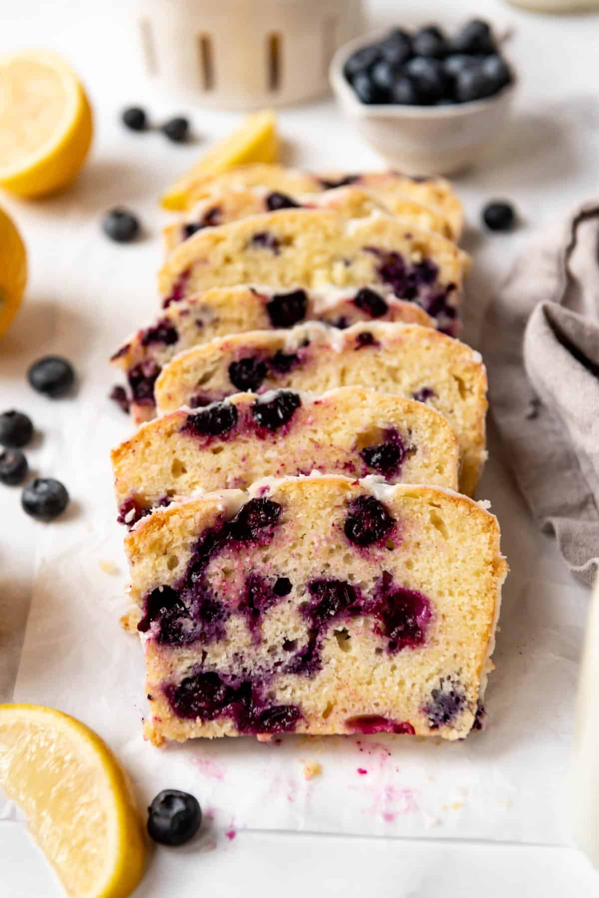 Slices of glazed lemon blueberry quick bread leaning against each other.