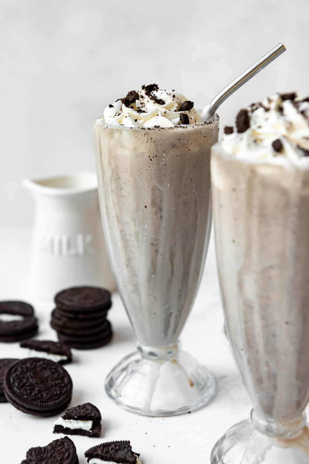 An Oreo milkshake with whipped cream, crushed Oreos, and a straw.