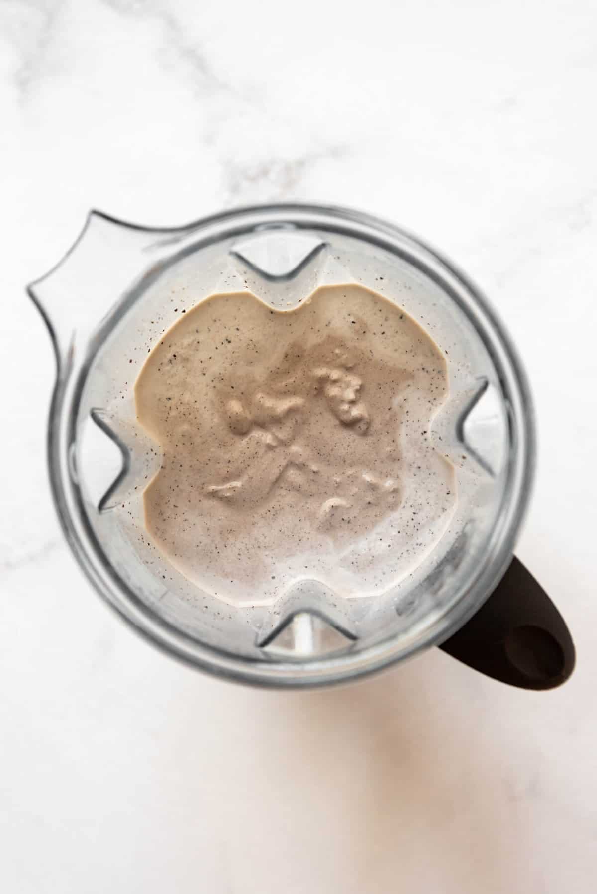 A blended Oreo milkshake in a Vitamix blender pitcher.