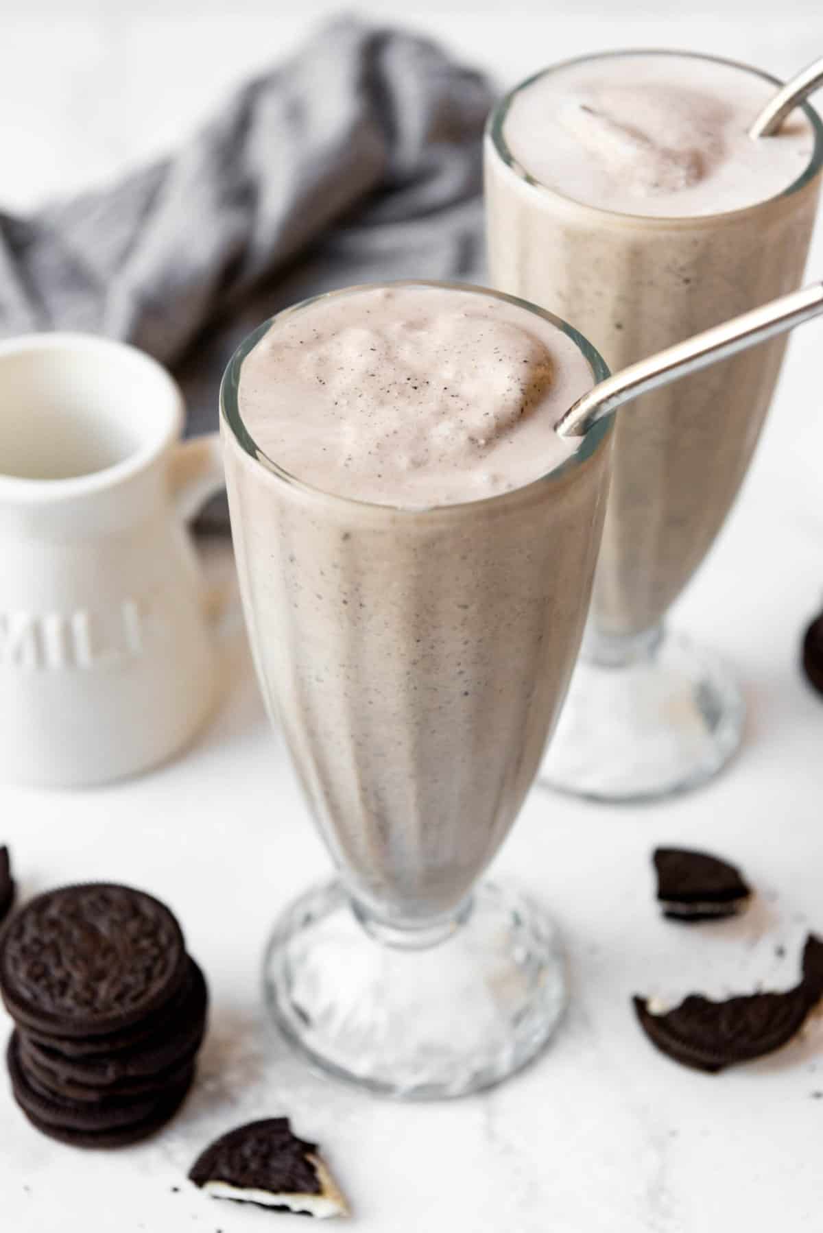 Two Oreo milkshakes in tall glasses with metal straws.