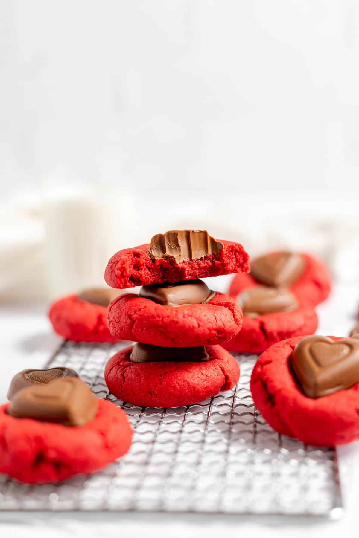 Three stacked red velvet kiss cookies with a bite taken out of the top one.