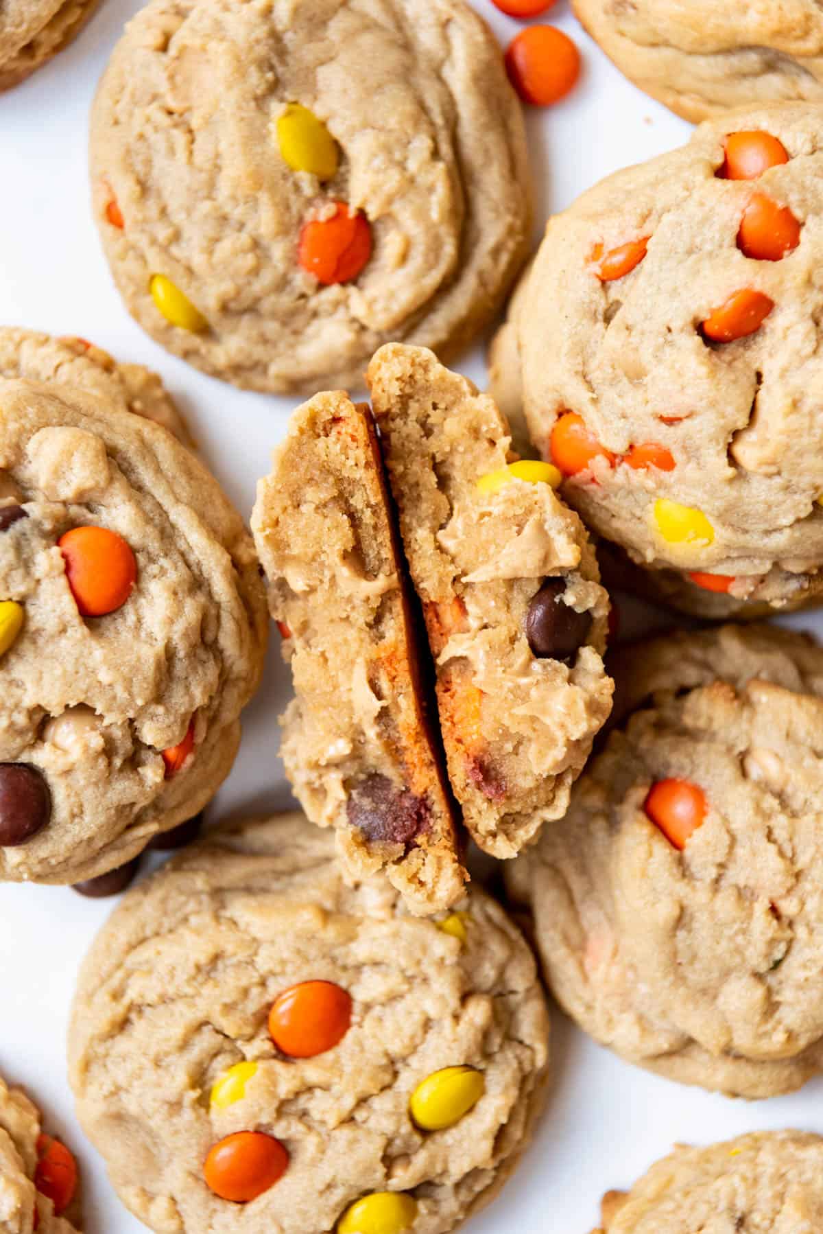 A Reese's Pieces cookie broken in half surrounded by more cookies.