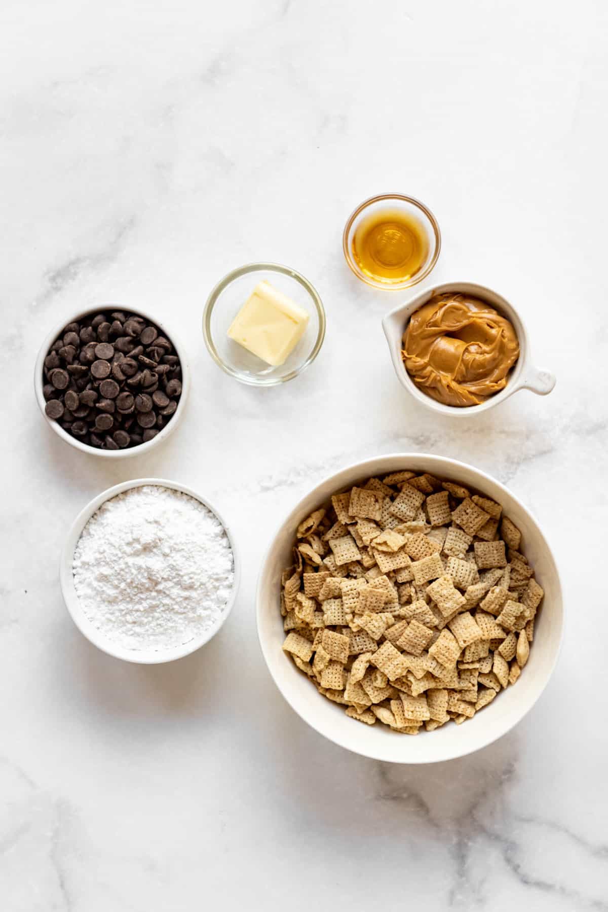 An overhead image of the ingredients for muddy buddies in various bowls.