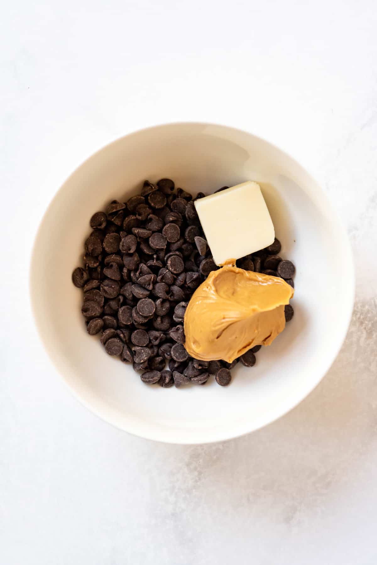 An image of chocolate, butter, and peanut butter ready to be melted in a bowl.