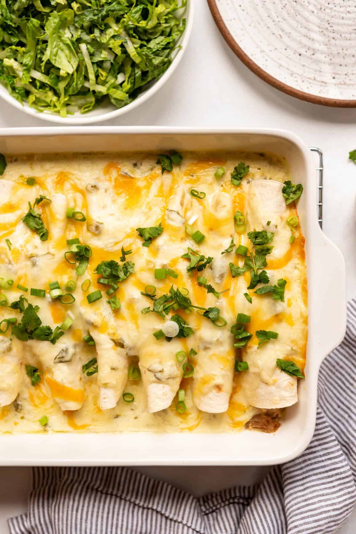 An overhead image of a baking dish of sour cream chicken enchiladas.