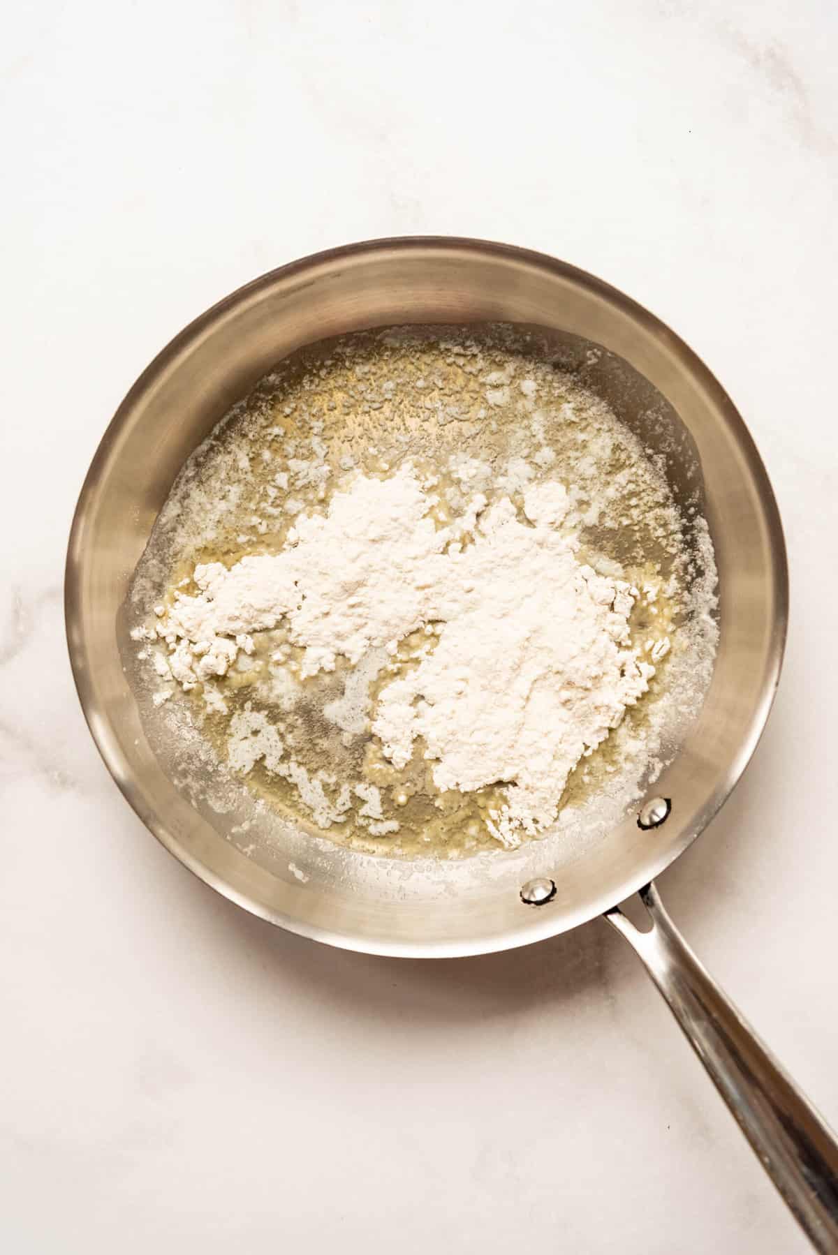 Adding flour to melted butter in a pan.