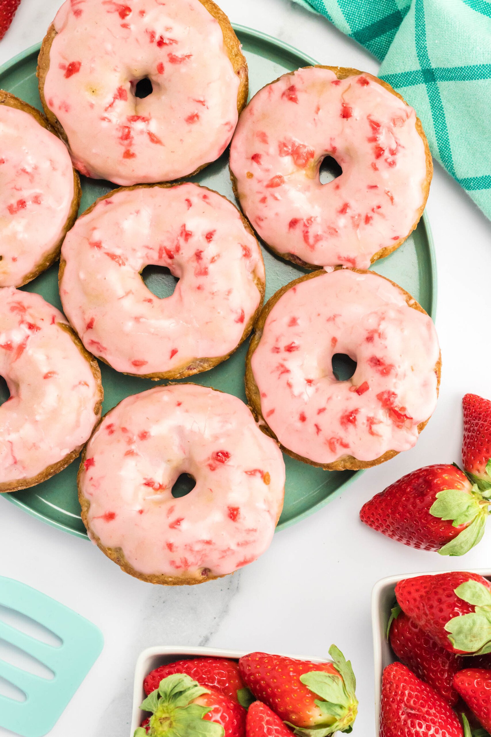 Top view of baked strawberry donuts on a plate.