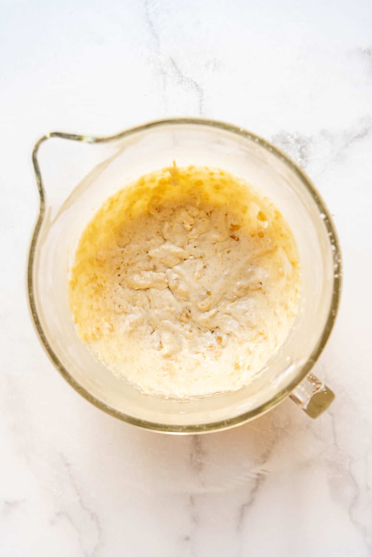 Mixing almond paste, softened butter, and sugar in a glass mixing bowl.