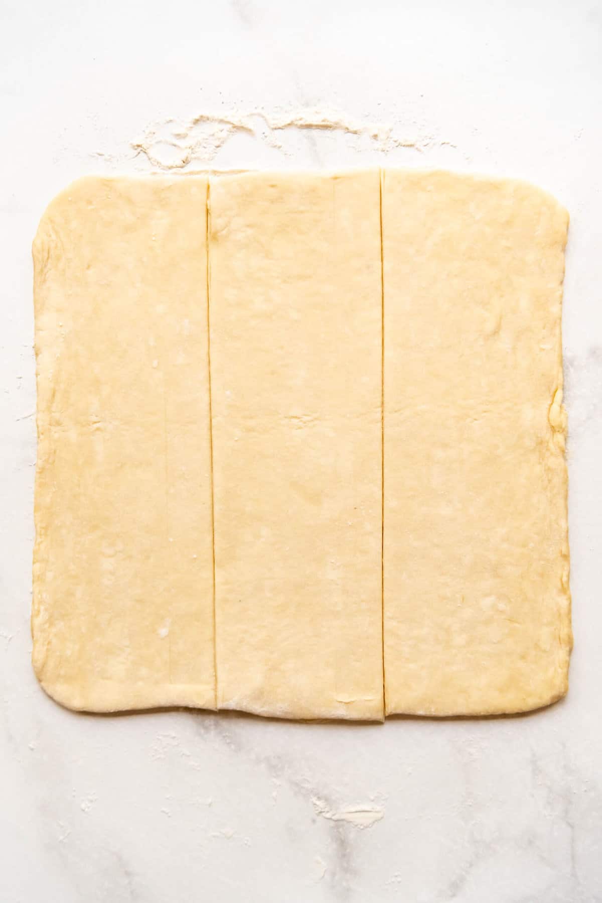 A square of bear claw dough sliced into thirds. 