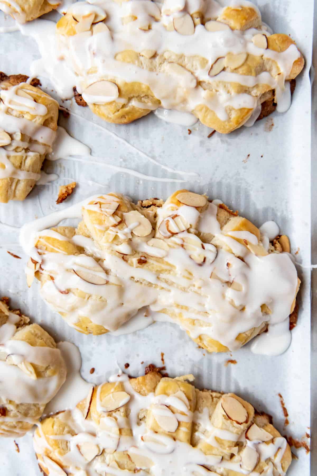 An overhead image of glazed almond bear claws on a baking sheet.