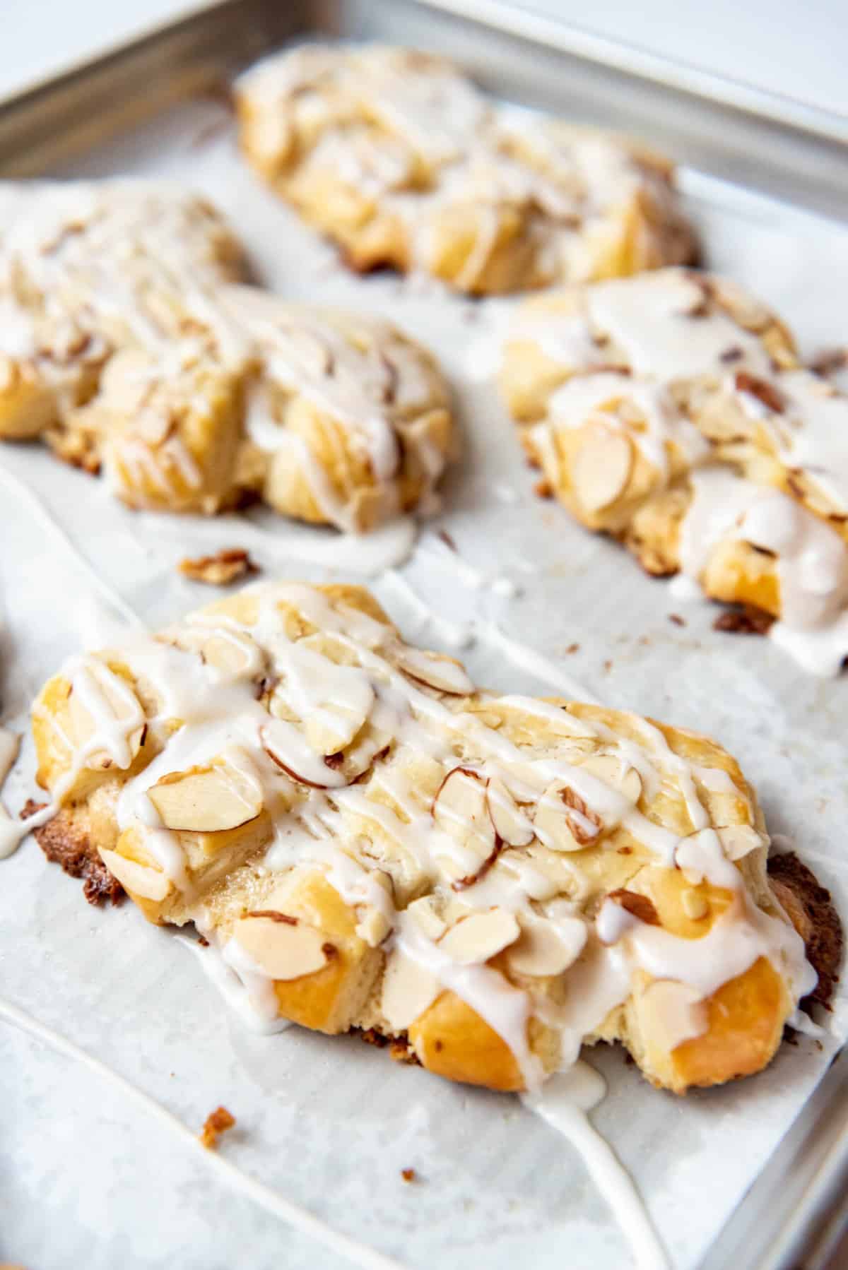 Homemade bear claws on a baking sheet lined with parchment paper.