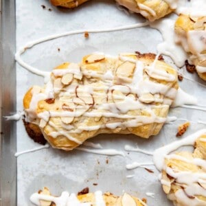A bear claw pastry with sliced almonds and glaze on top.