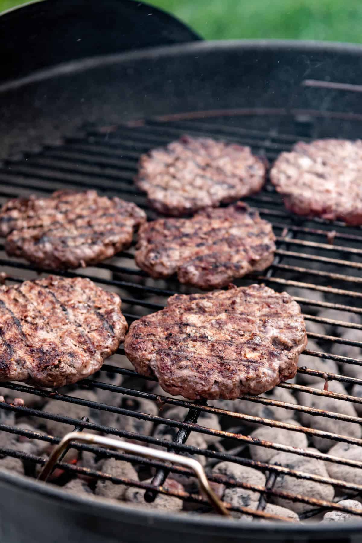 Flipping bison burgers on a charcoal grill.