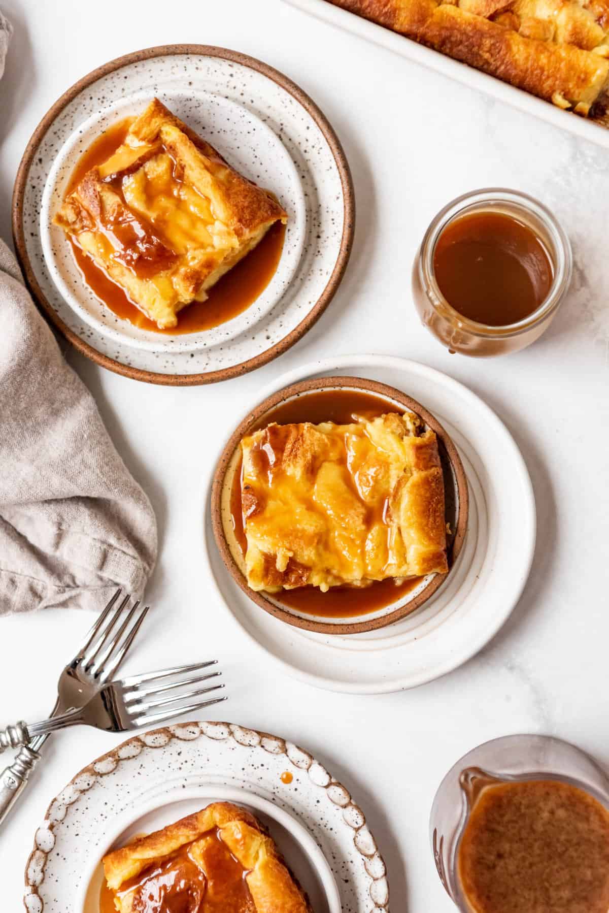 An overhead image of slices of bread pudding on plates with caramel sauce.