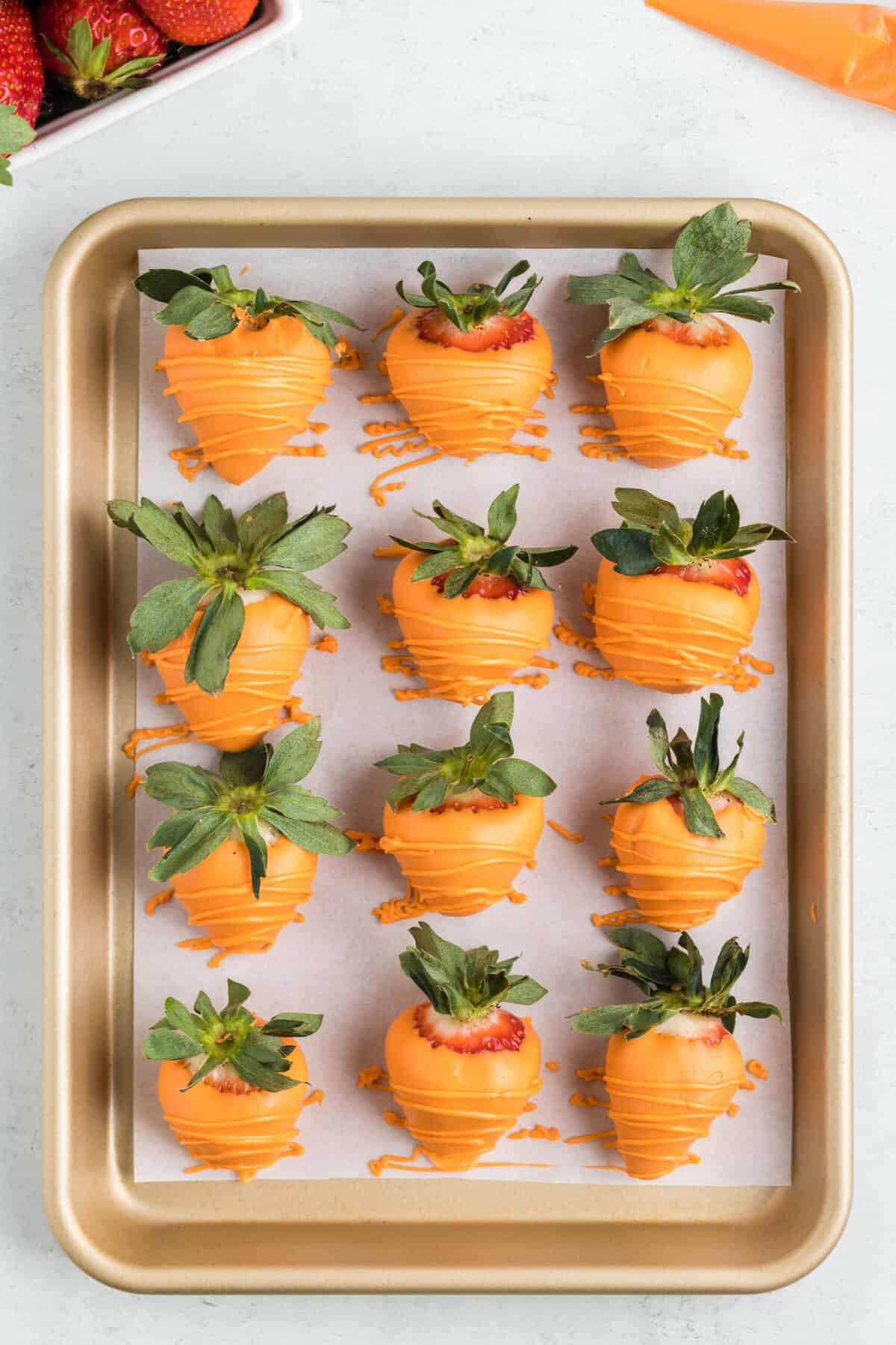 A dozen Easter chocolate covered strawberries on a baking sheet lined with parchment paper.