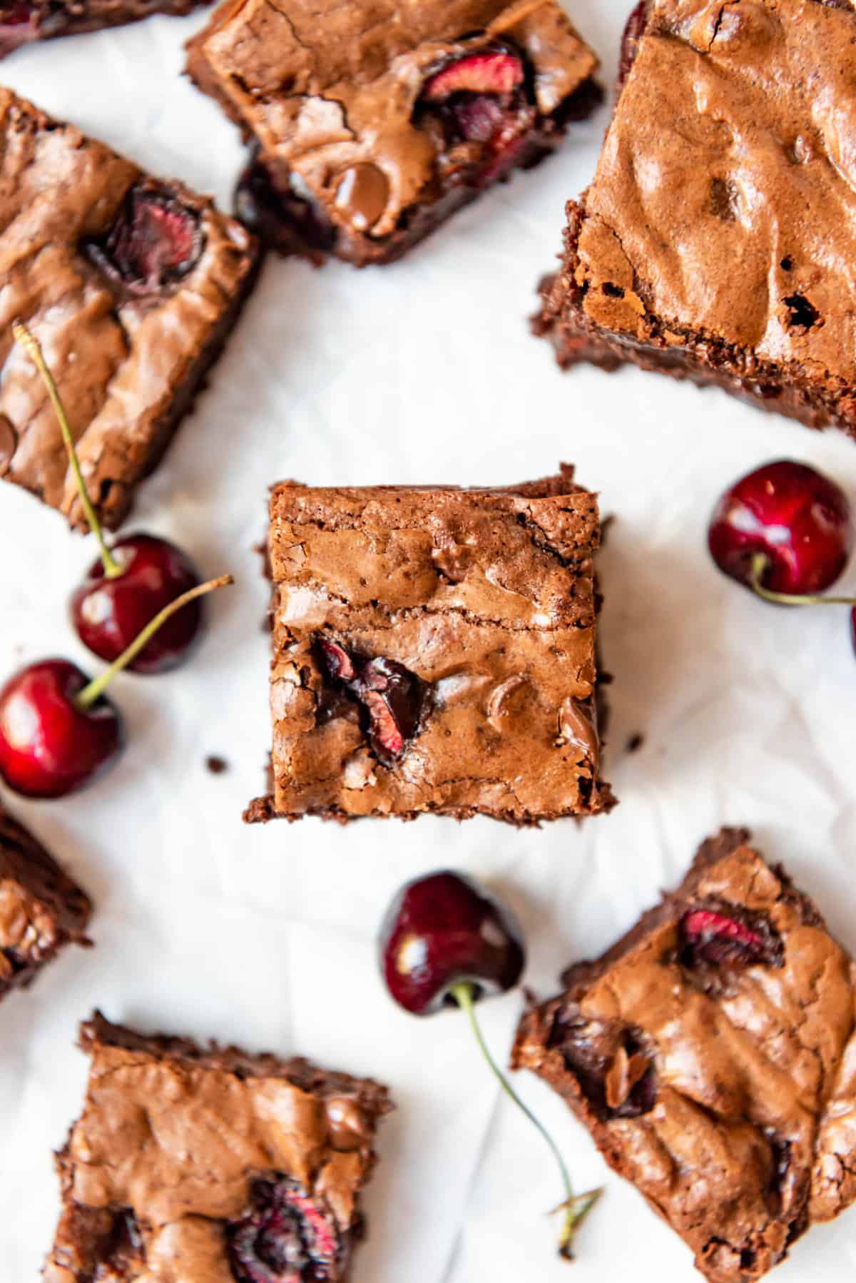 An overhead image of cherry brownies with bing cherries around them.