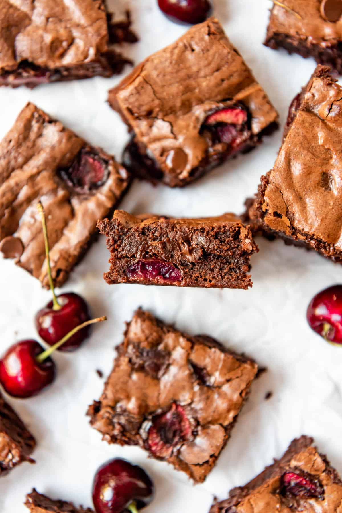 A cherry brownie turned on its side to show the fudge middle studded with cherries and chocolate chips.