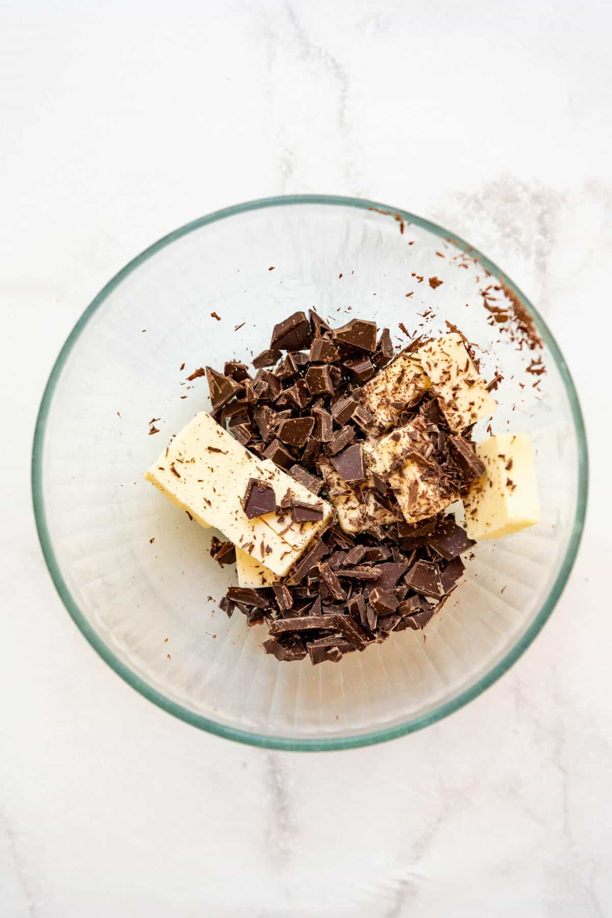 Combining chopped chocolate and butter in a large glass mixing bowl.