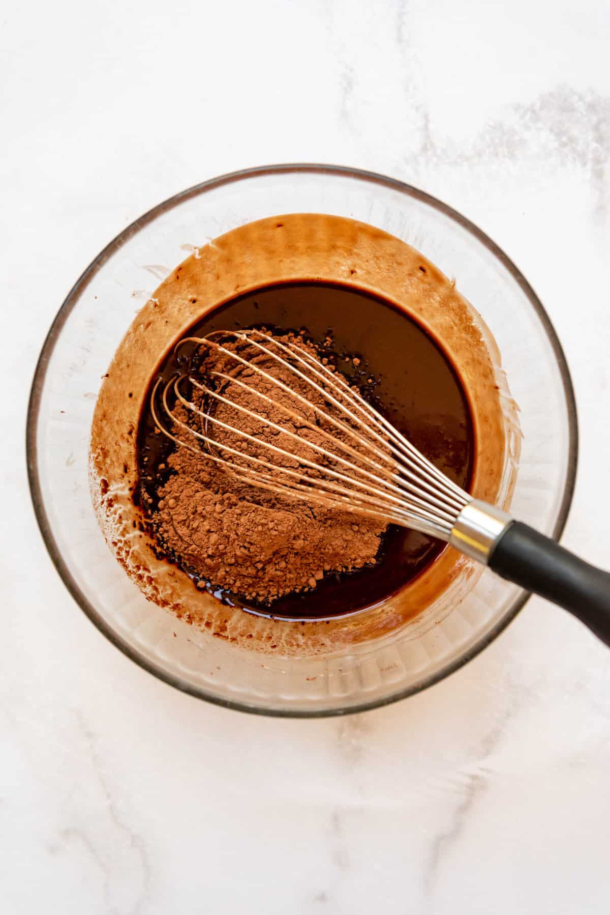 Whisking cocoa powder into melted butter and chocolate.